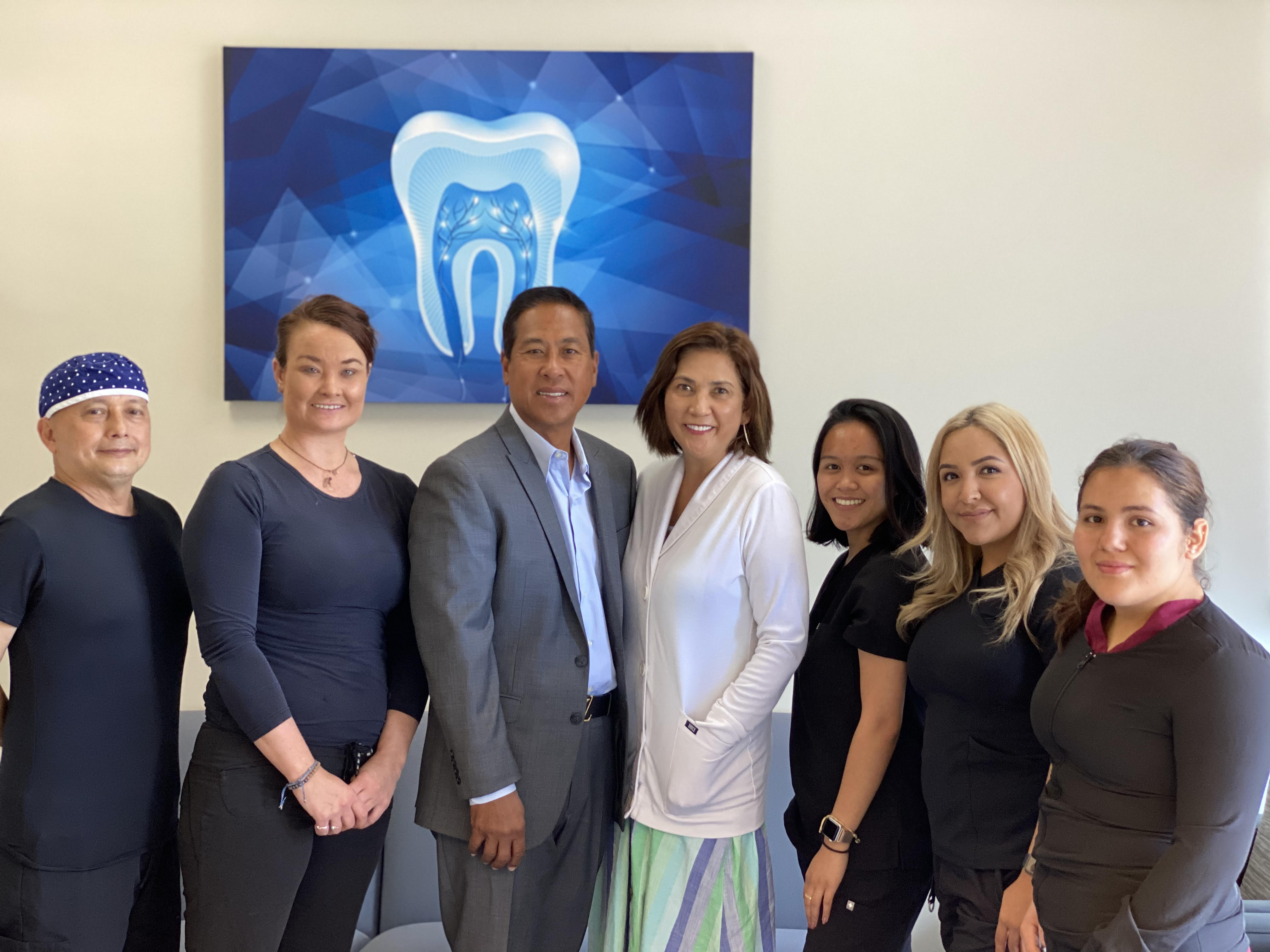 Dr. Ron E. Quibilan, Mila Quibilan, and the chairside team of seven standing together in the Sunnyvale waiting area.